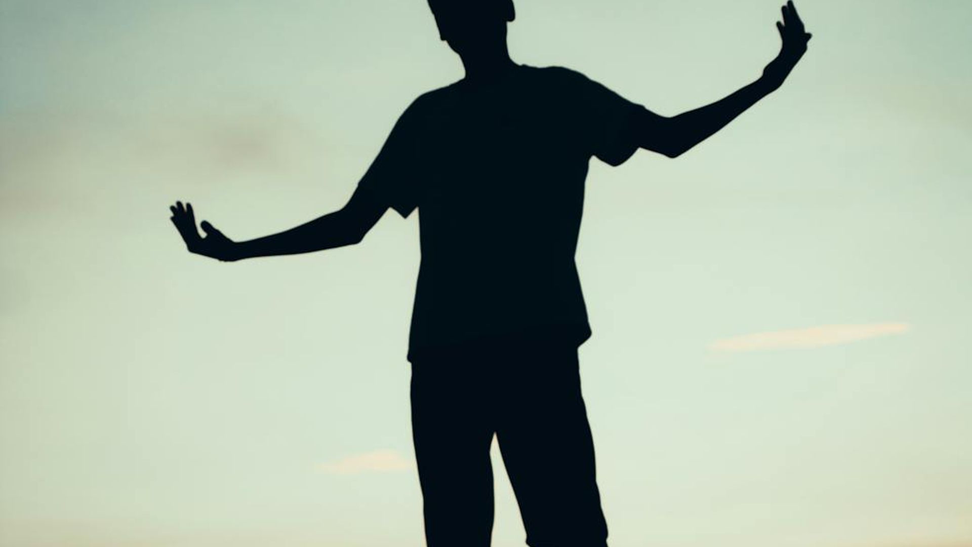 Silhouette of a person in a calm, balanced yoga pose against a dark, serene background.